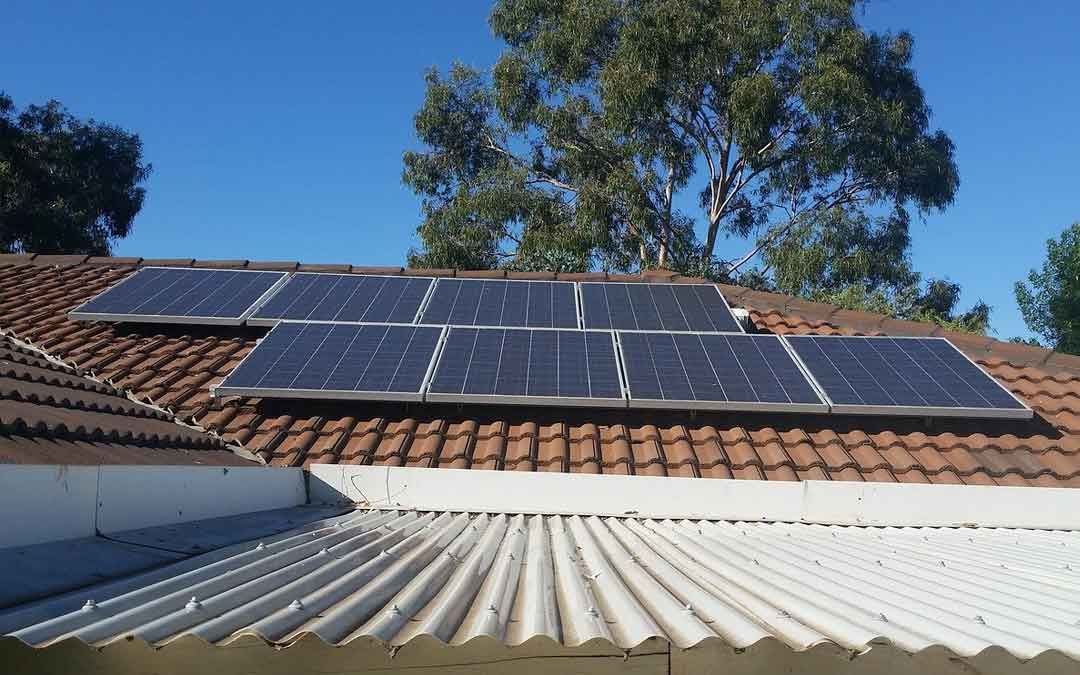 solar panels on a tiled roof with a tree in the background